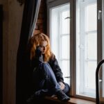 woman in black leather jacket sitting on brown wooden floor